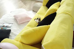 Close-up of bright yellow plush rabbit fur sofa cover with matching decorative pillows
