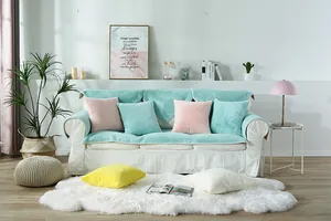 Detail of mint green plush sofa cover and soft faux rabbit fur cushions in a cozy living room