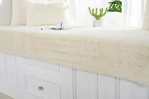 Dettaglio del tappeto per finestra in morbido peluche bianco e cuscino in ecopelliccia