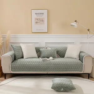 Detail of dark green quilted velvet sofa cover with white lace trim and floral patterns