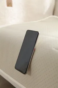 Gros plan d'un smartphone doré avec écran goutte d'eau sur un tapis en peluche beige