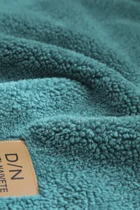 Gros plan sur un tissu polaire bleu mer épais avec une étiquette en cuir marron de qualité