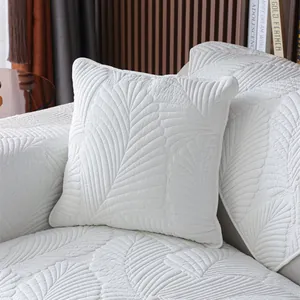 Détail d'une housse de canapé matelassée blanc ivoire avec motif de feuilles et texture douce