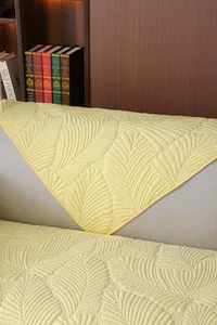 Détail de la housse de canapé matelassée en coton jaune avec motif de feuilles brodé