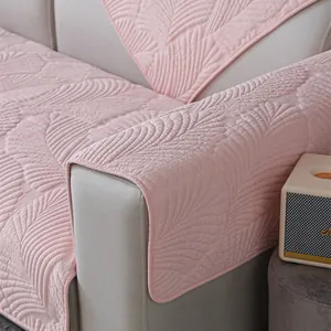 Détail d'un coussin de canapé matelassé rose avec motif de feuilles et bords antidérapants