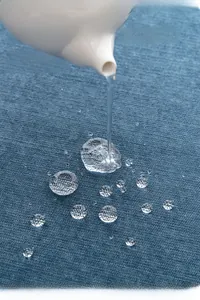 Nahaufnahme von blauem wasserdichtem Stoff mit Wassertropfen und Fleckschutzstruktur