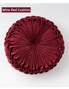 Detailed view of the pleated velvet wheel cushion in wine red with a center button