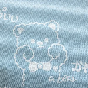 Close-up of light blue cotton linen fabric texture with cartoon bear print pattern