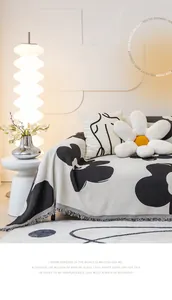 Detail of knit sofa cover with black and white floral pattern and decorative fringe
