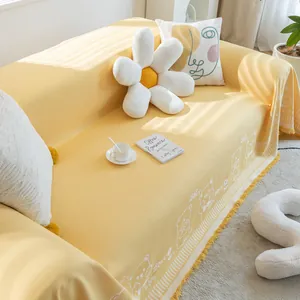 Detail of yellow cotton sofa cover featuring cartoon bear patterns and decorative tassels