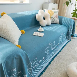 Close-up of blue linen sofa cover featuring white cartoon bears and fringe tassels