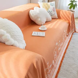 Detail of orange cotton linen sofa throw with knit texture, bear pattern, and fringes