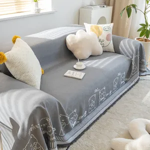 Close-up of grey cotton linen sofa cover featuring cute cartoon bear and fringe edges