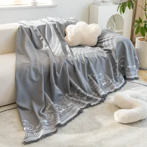 Detail of grey cotton linen sofa cover featuring cute cartoon bear pattern and fringe