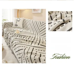 Detail of cream sofa cover with black geometric patterns, knit texture and tassels