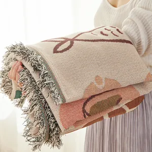 Detail of jacquard woven sofa throw featuring abstract patterns and soft mixed tassels