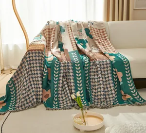 Detail of bohemian knit throw blanket with floral patterns and delicate fringe on a sofa