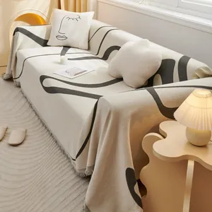 Detailed view of chenille sofa cover with abstract face patterns and tassel edges