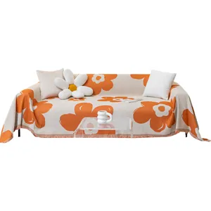 Knit floral sofa cover with fringe edges and orange flower patterns in cream color