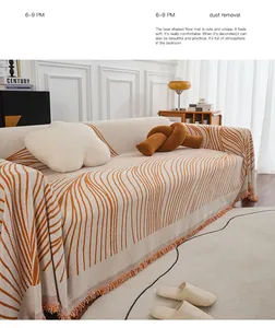 Detail of orange wave pattern chenille sofa throw with decorative tassels and texture