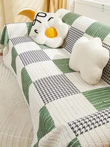 Close-up of green and white checkerboard chenille sofa cover with tassel fringe and texture