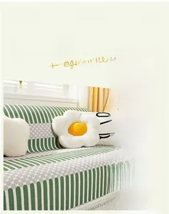 Detail of lime green and white geometric sofa cover with fringe and daisy pillow