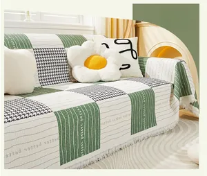 Close-up of green checkered cat-proof sofa cover with tassels and letter prints