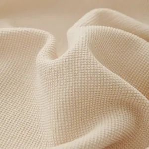 Detailed macro view of soft cream waffle knit sofa cover fabric texture and weave