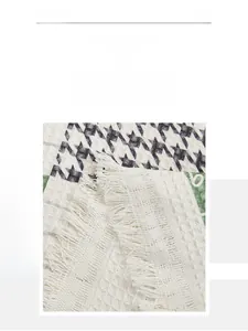 Macro detail of houndstooth cotton sofa cover with woven tassels and textured fabric