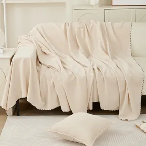 Minimalist beige sofa cover with scalloped edges and textured knit fabric on a couch
