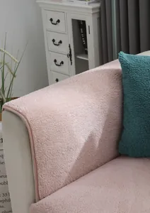 Primer plano de la funda de sofá de lana de cordero rosa con textura suave y cojín azul