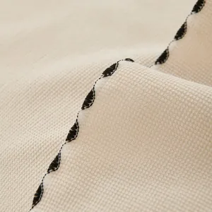 Beige waffle weave sofa cover blanket with decorative black wavy edge stitching