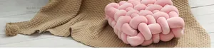 Gros plan d'un coussin décoratif noué rose fait main sur une couverture texturée