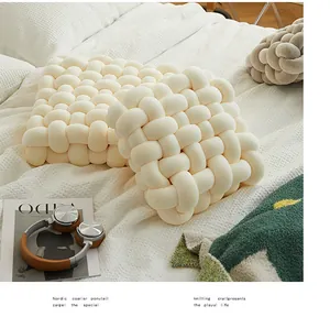 Vue détaillée de la texture tissée à la main d'un coussin à nœud crème au style minimaliste