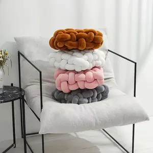 Coussins nöuds tissés modernes en plusieurs couleurs empilés sur un fauteuil gris