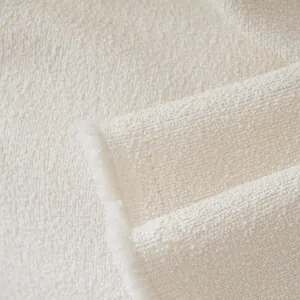 Close-up of cream bouclé sofa cover fabric with textured granules and fringed edges