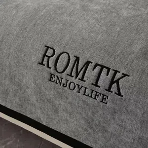 Housse de canapé grise en chenille avec broderie ROMTK sur une texture de tissu tissé