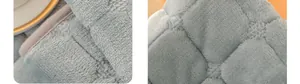Dettaglio macro del cuscino in peluche azzurro con trapuntatura a quadri e bordo grigio
