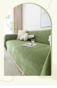 Detail of dark green chenille sofa cover with herringbone pattern and colorful pom-poms