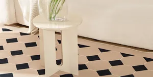 Minimalist cream round side table with U-shaped legs on a modern geometric rug