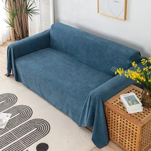 Dettaglio del copridivano in ciniglia blu con frange a pompon bicolore in un interno