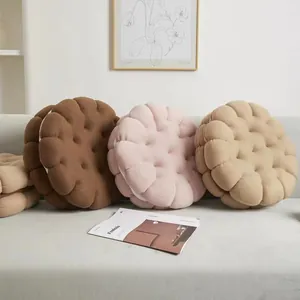 Round biscuit-shaped plush pillows in brown, khaki, and pink colors for home decor