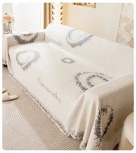 Gros plan du jeté de canapé en tricot blanc crème avec motif de feux d'artifice et pompons