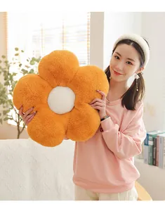 Détail d'un coussin tournesol en peluche orange avec un centre blanc sur canapé