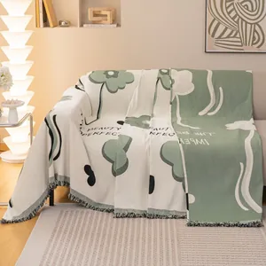 Copridivano in ciniglia beige e verde con motivi floreali e bordi a frange nere