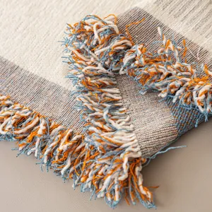 Copridivano boho in ciniglia con trama arancione e blu e nappine sfrangiate