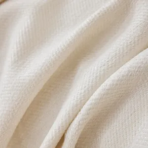 Macro view of beige chenille fabric showing the soft herringbone weave texture and detail