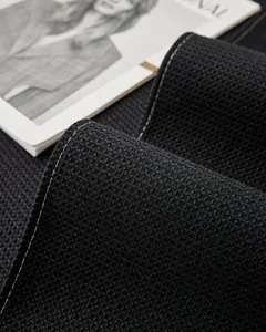 Gros plan sur un tissu gaufré noir montrant des coutures fines et une texture alvéolée