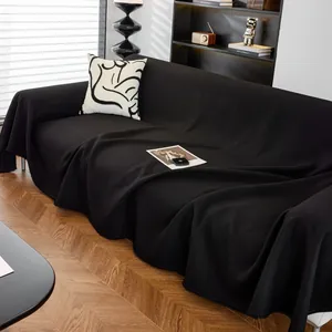 Funda de sofá moderna de gofre negro con borlas en un sofá minimalista oscuro