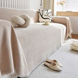 Close-up of beige waffle weave texture on thick chenille sofa cover with fringed edges